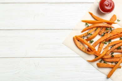 Photo of Tasty sweet potato fries on wooden background, top view. Space for text