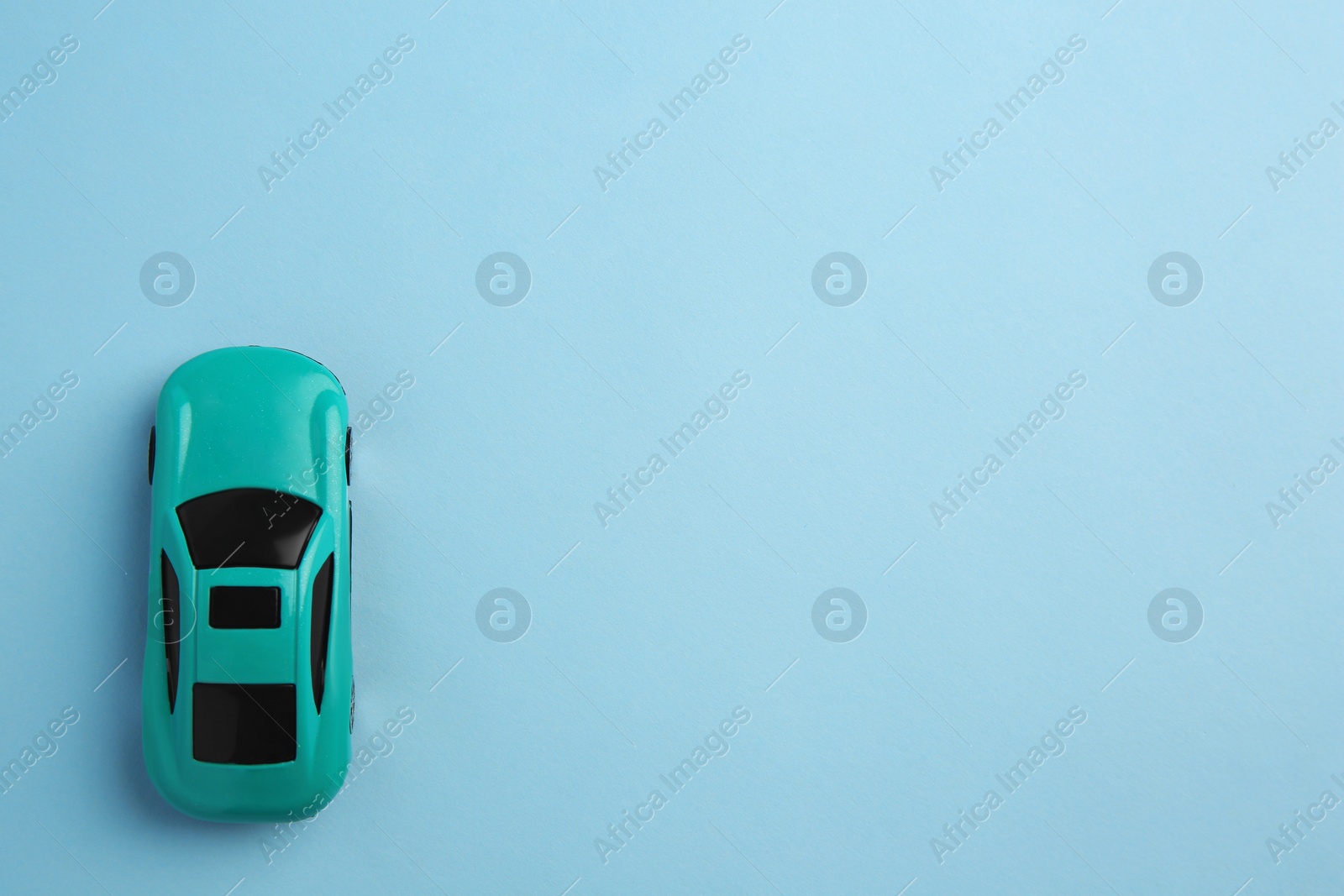 Photo of One bright car on light blue background, top view with space for text. Children`s toy