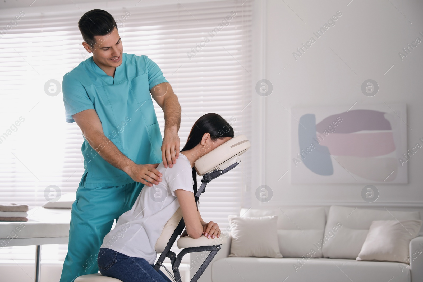 Photo of Woman receiving massage in modern chair indoors