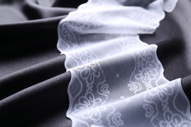 Beautiful white lace on black fabric, closeup