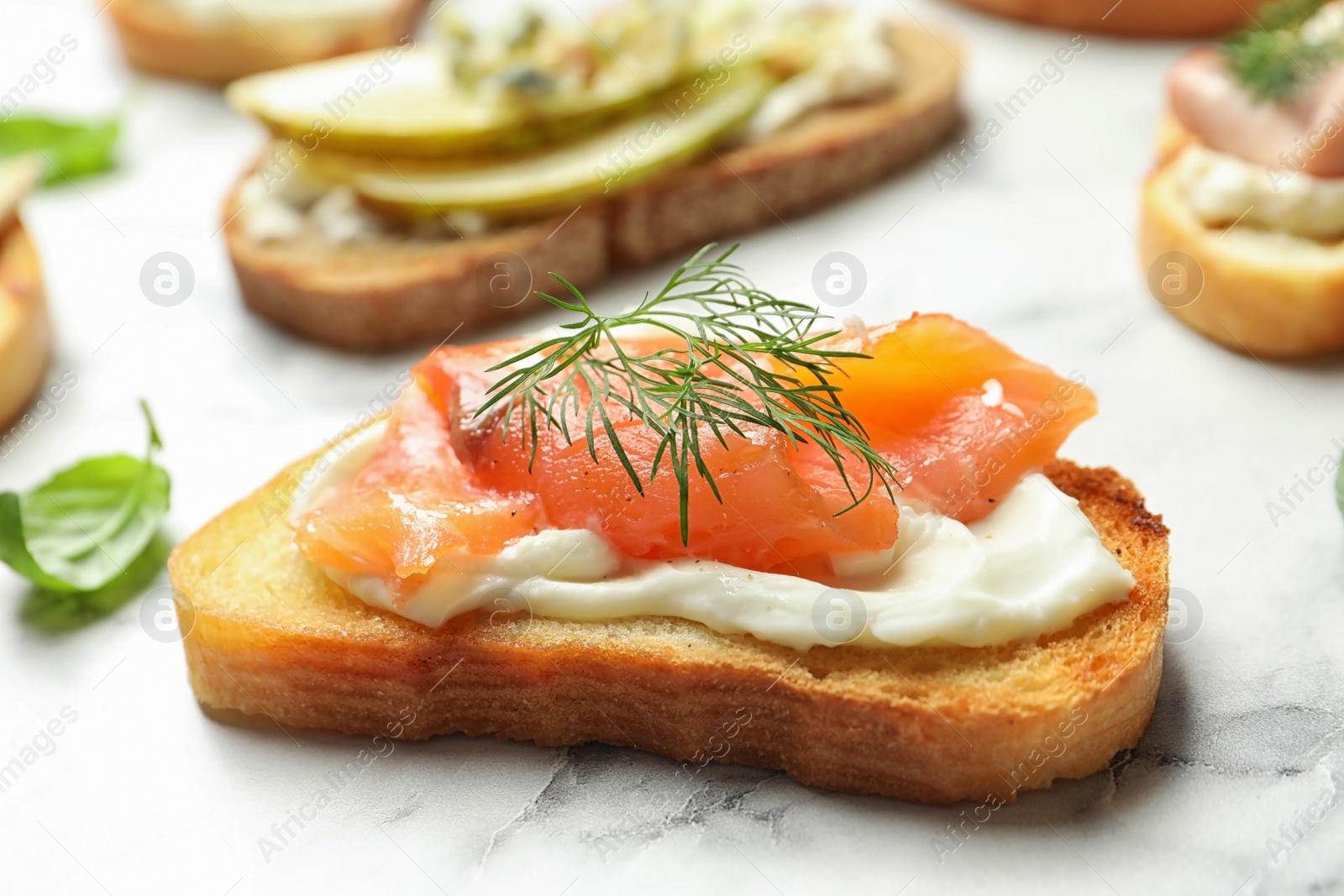 Photo of Tasty bruschetta with salmon on marble table