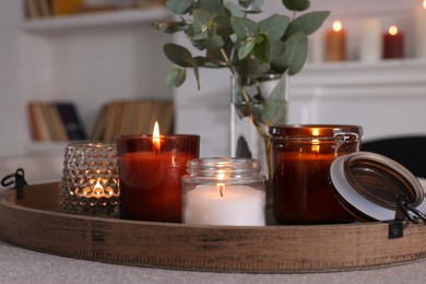 Photo of Tray with beautiful burning candles and vase on table indoors