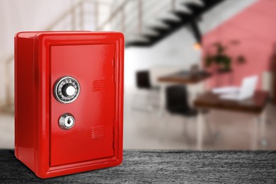 Image of Red closed steel safe with mechanical lock on black table indoors. Space for text