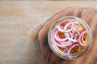 Jar of pickled onions on wooden table, top view. Space for text