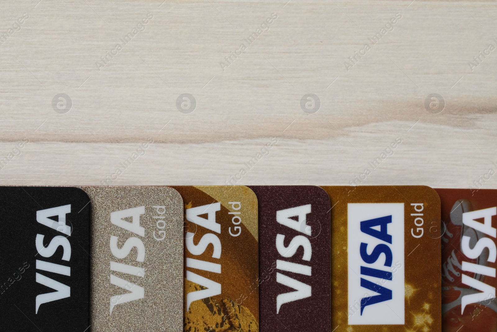 Photo of MYKOLAIV, UKRAINE - FEBRUARY 22, 2022: Visa credit cards on white wooden table, flat lay. Space for text