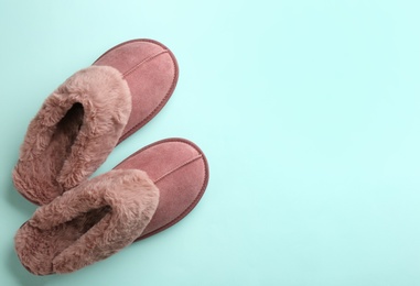 Pair of stylish soft slippers on turquoise background, flat lay. Space for text