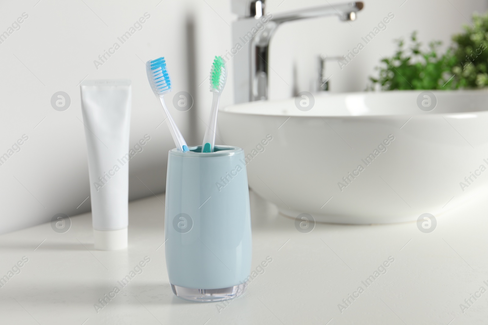 Photo of Plastic toothbrushes on white countertop in bathroom, space for text