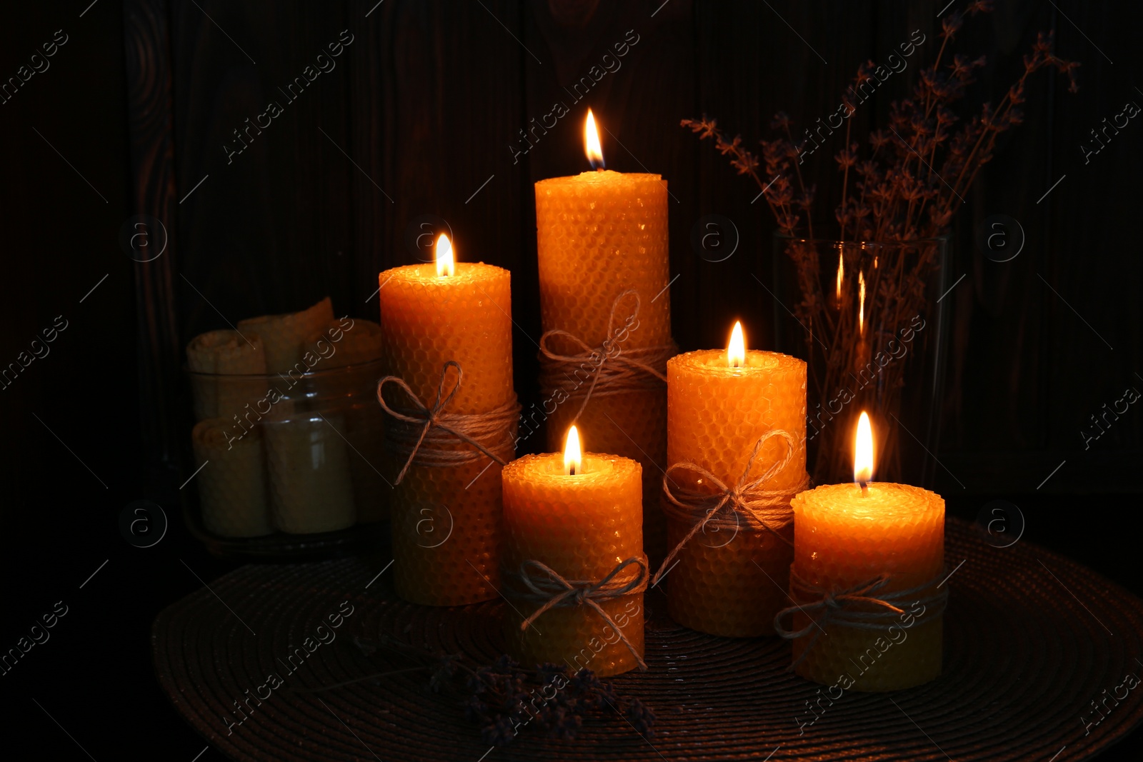 Photo of Beautiful burning beeswax candles and dried lavender flowers on table