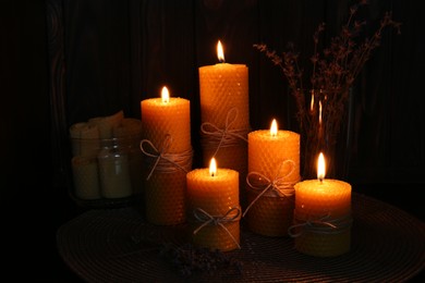 Photo of Beautiful burning beeswax candles and dried lavender flowers on table