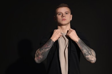Photo of Young man with tattoos on black background