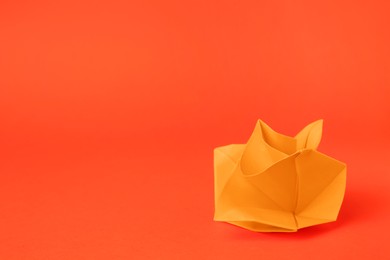Photo of Origami art. Handmade bright paper flower on orange background, space for text