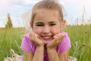Photo of Cute little girl in green field, closeup