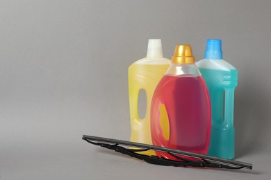 Photo of Bottles of windshield washer fluids and wiper on grey background. Space for text