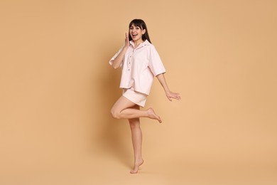 Photo of Happy woman wearing pyjama on beige background