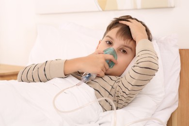 Photo of Boy using nebulizer for inhalation on bed at home