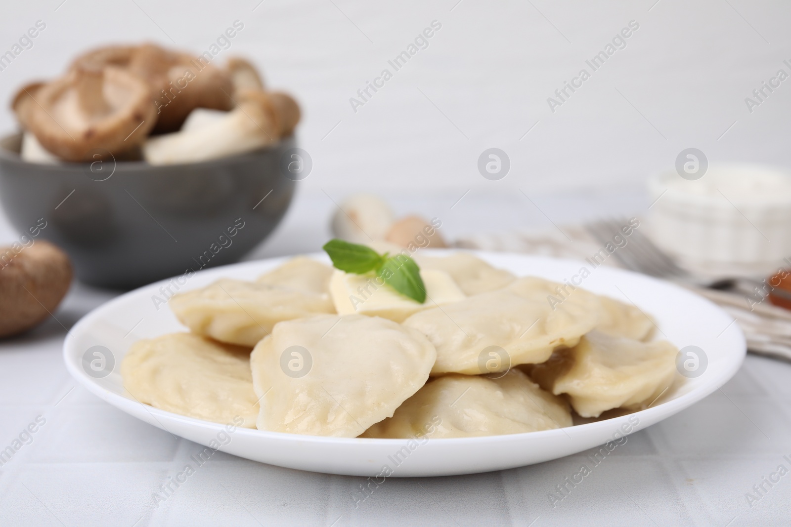 Photo of Delicious dumplings (varenyky) with tasty filling and butter on white tiled table, closeup