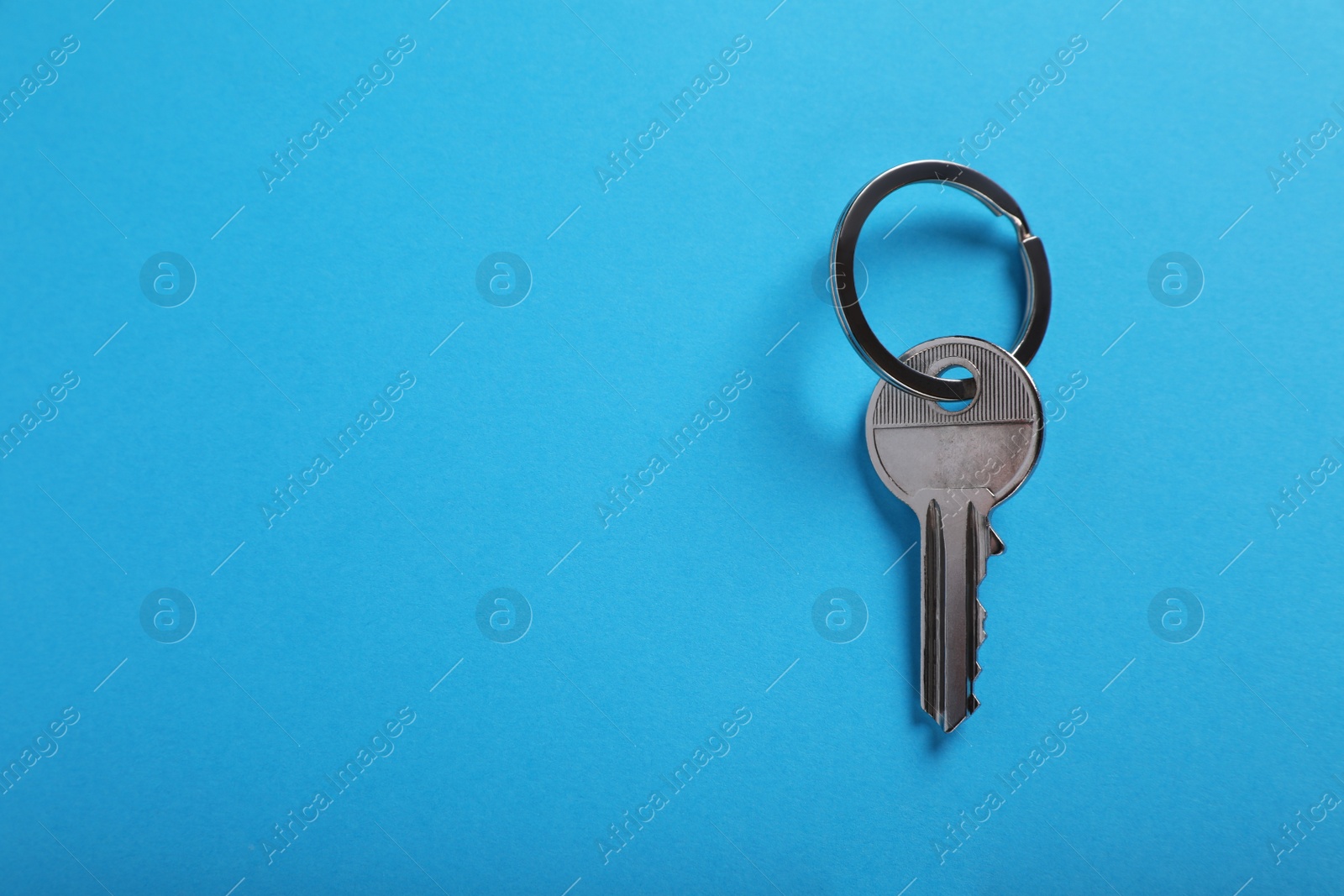 Photo of House key on light blue background, top view with space for text. Real estate agent services