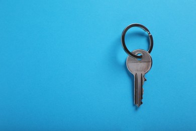 House key on light blue background, top view with space for text. Real estate agent services