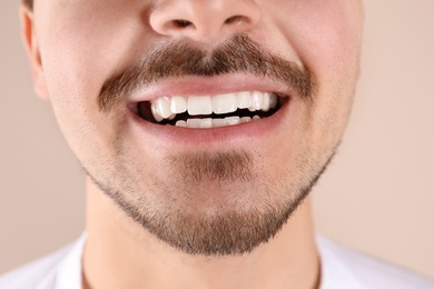 Photo of Young man with healthy teeth smiling on color background, closeup