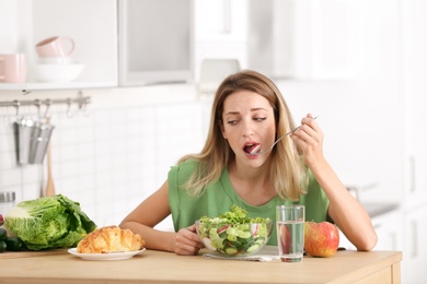 Woman choosing between vegetable salad and dessert in kitchen. Healthy diet