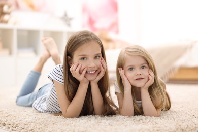 Photo of Cute little sisters on floor at home