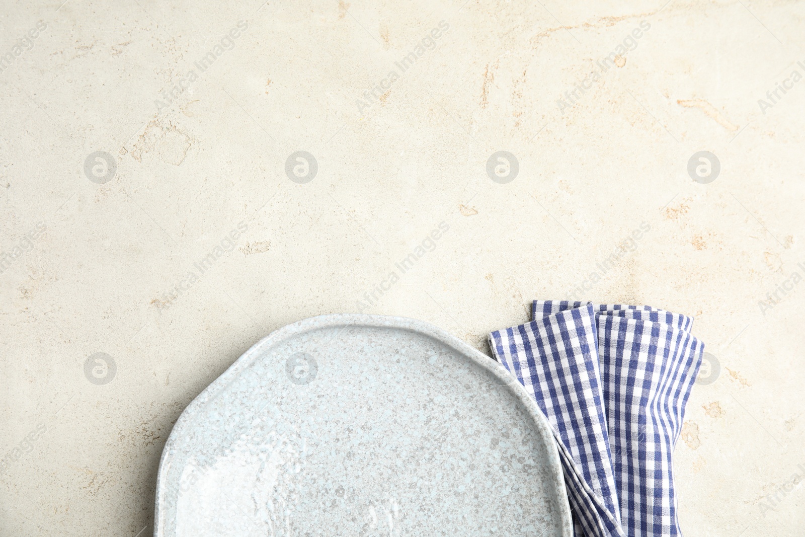 Photo of Empty plate and napkin on light table, top view. Space for text