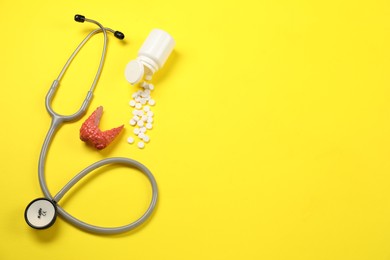 Photo of Endocrinology. Stethoscope, bottle with pills and model of thyroid gland on yellow background, flat lay. Space for text