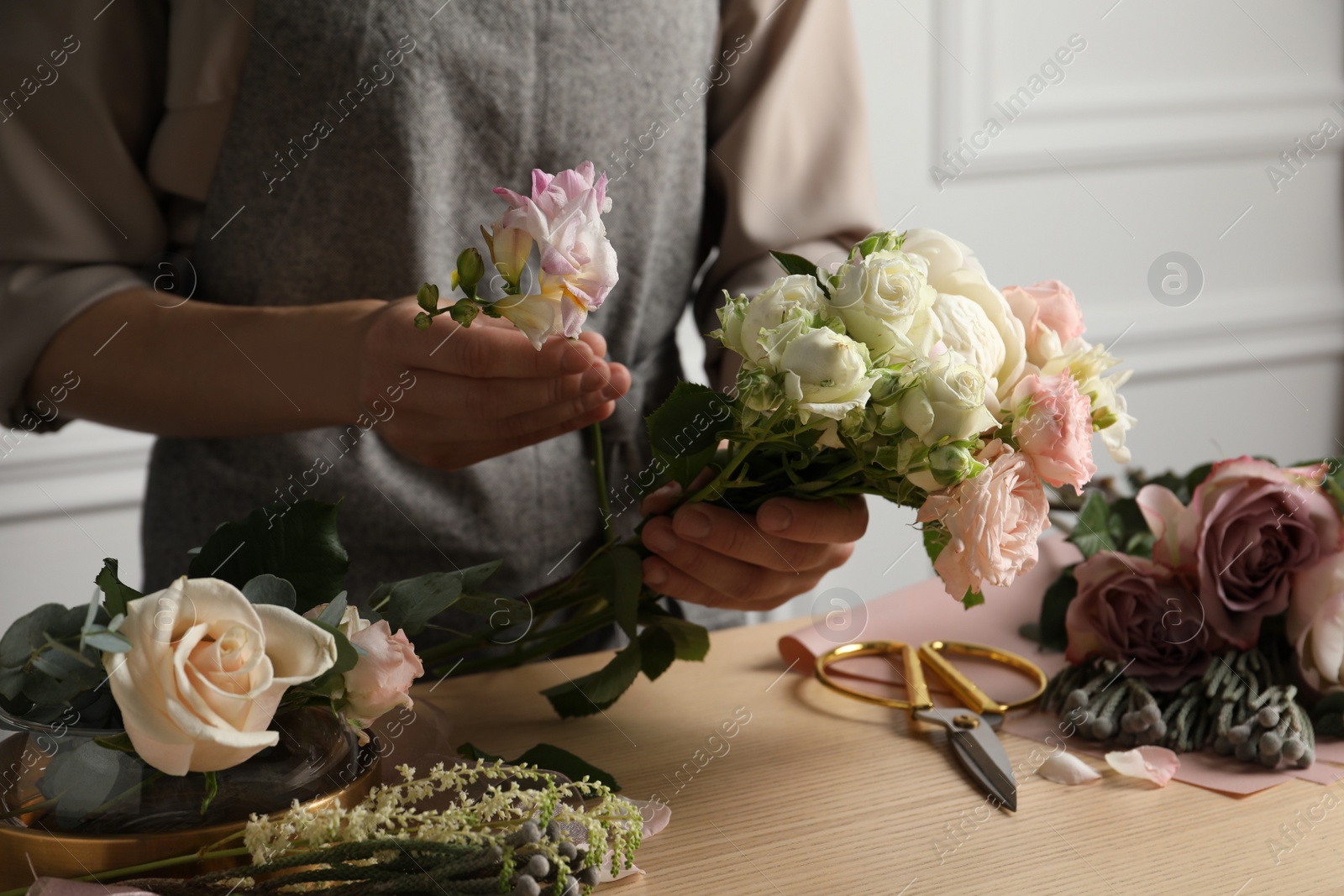 Photo of Florist creating beautiful bouquet at wooden table indoors, closeup