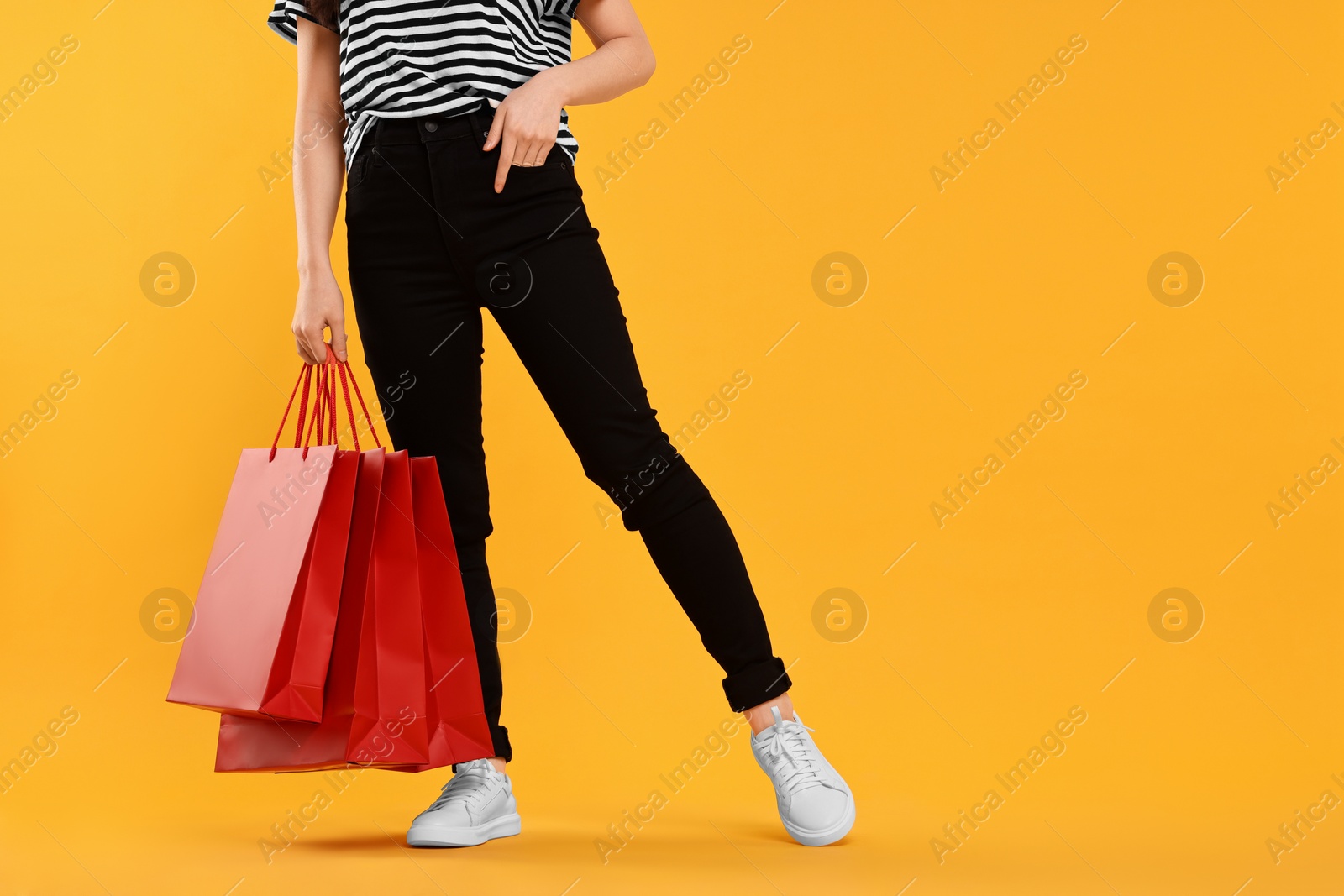 Photo of Woman with shopping bags on yellow background, closeup. Space for text