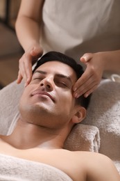 Man receiving facial massage in beauty salon