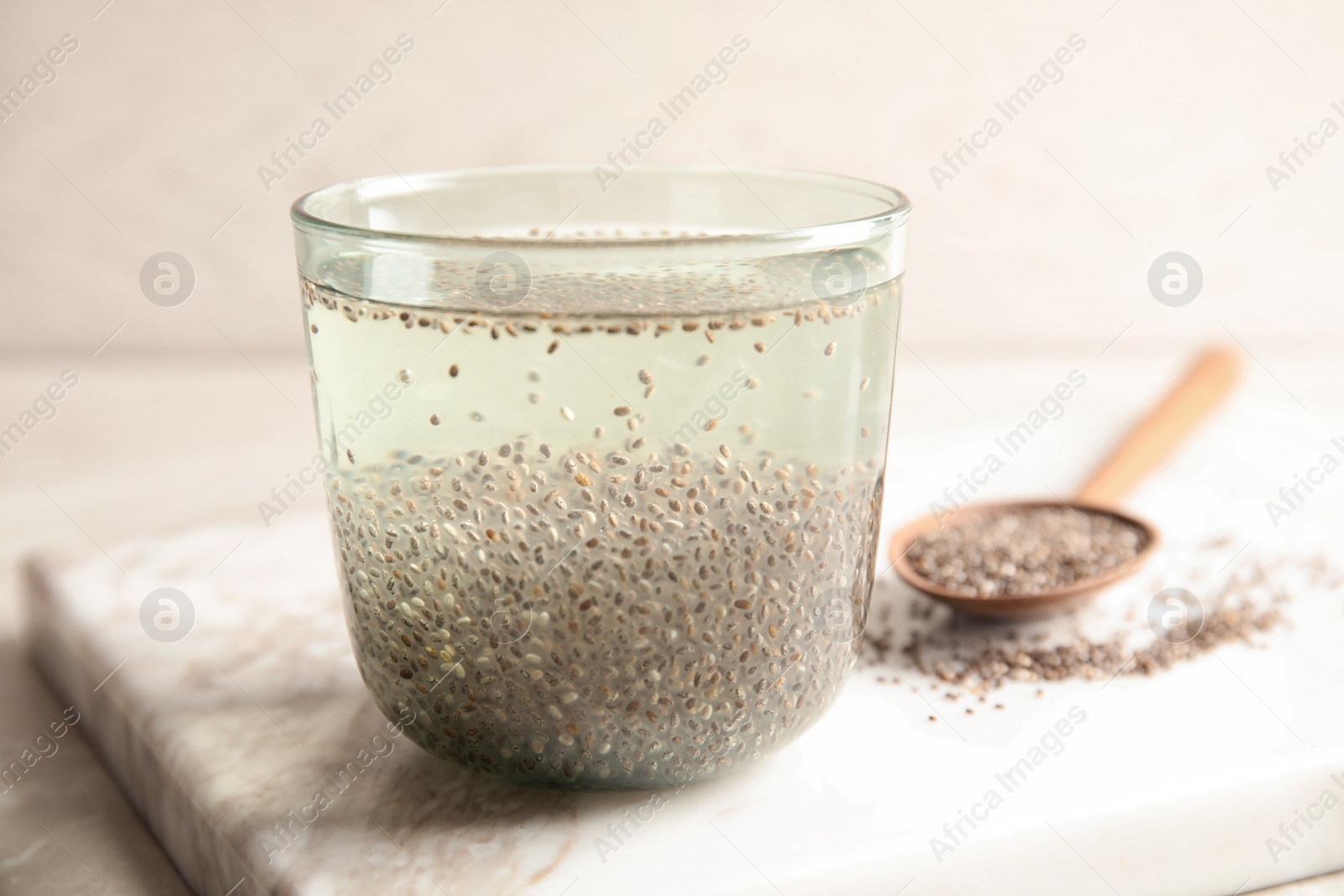 Photo of Glass of water with chia seeds and spoon on board