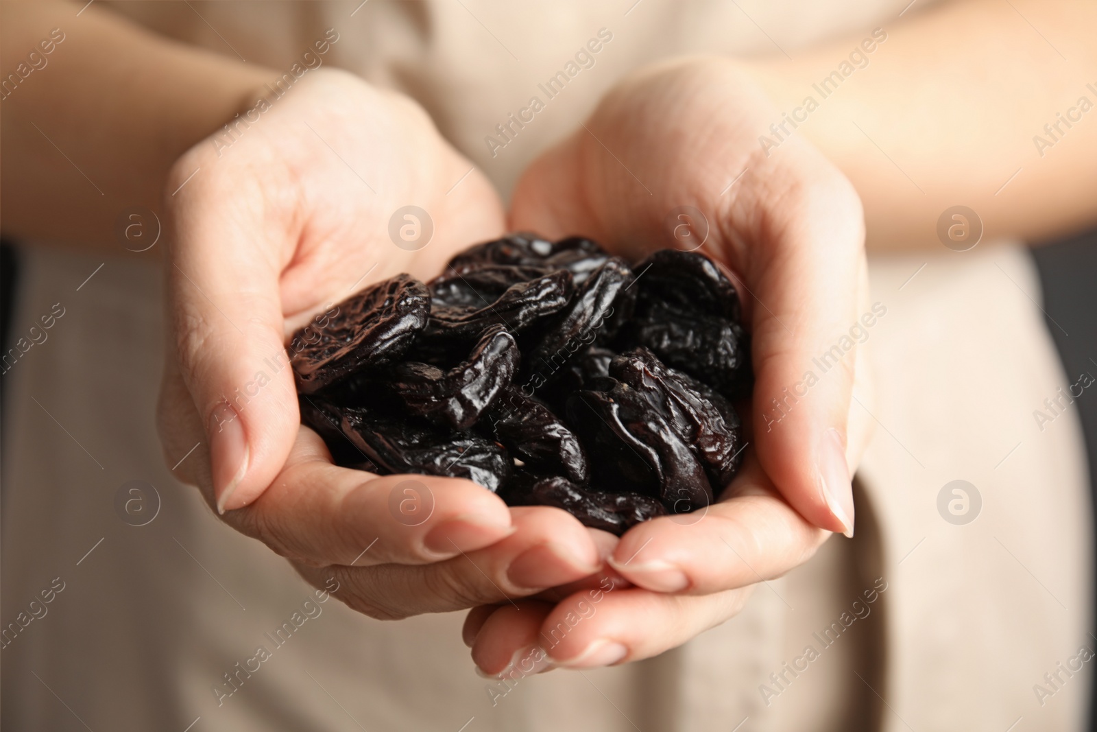 Photo of Woman holding handful of dried plums, closeup. Healthy fruit