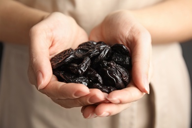 Woman holding handful of dried plums, closeup. Healthy fruit