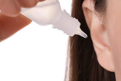 Woman using ear drops on white background, closeup