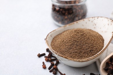 Aromatic clove powder and dried buds on light table, closeup. Space for text