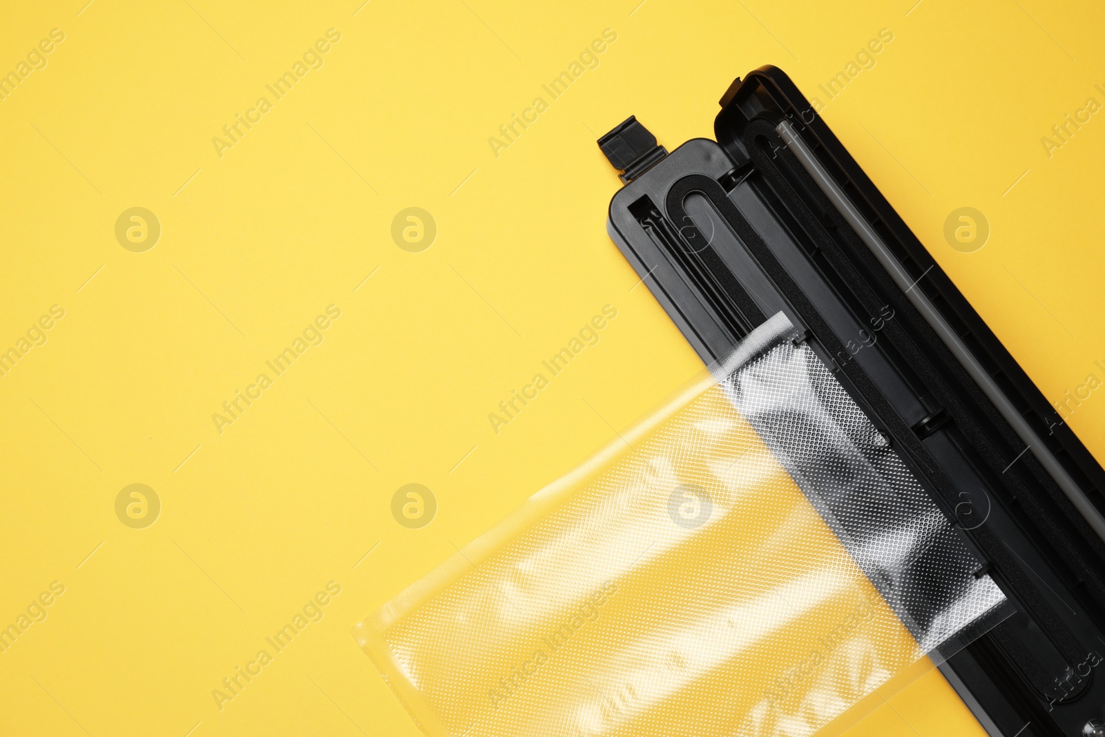 Photo of Sealer for vacuum packing with plastic bag on light yellow background, flat lay. Space for text