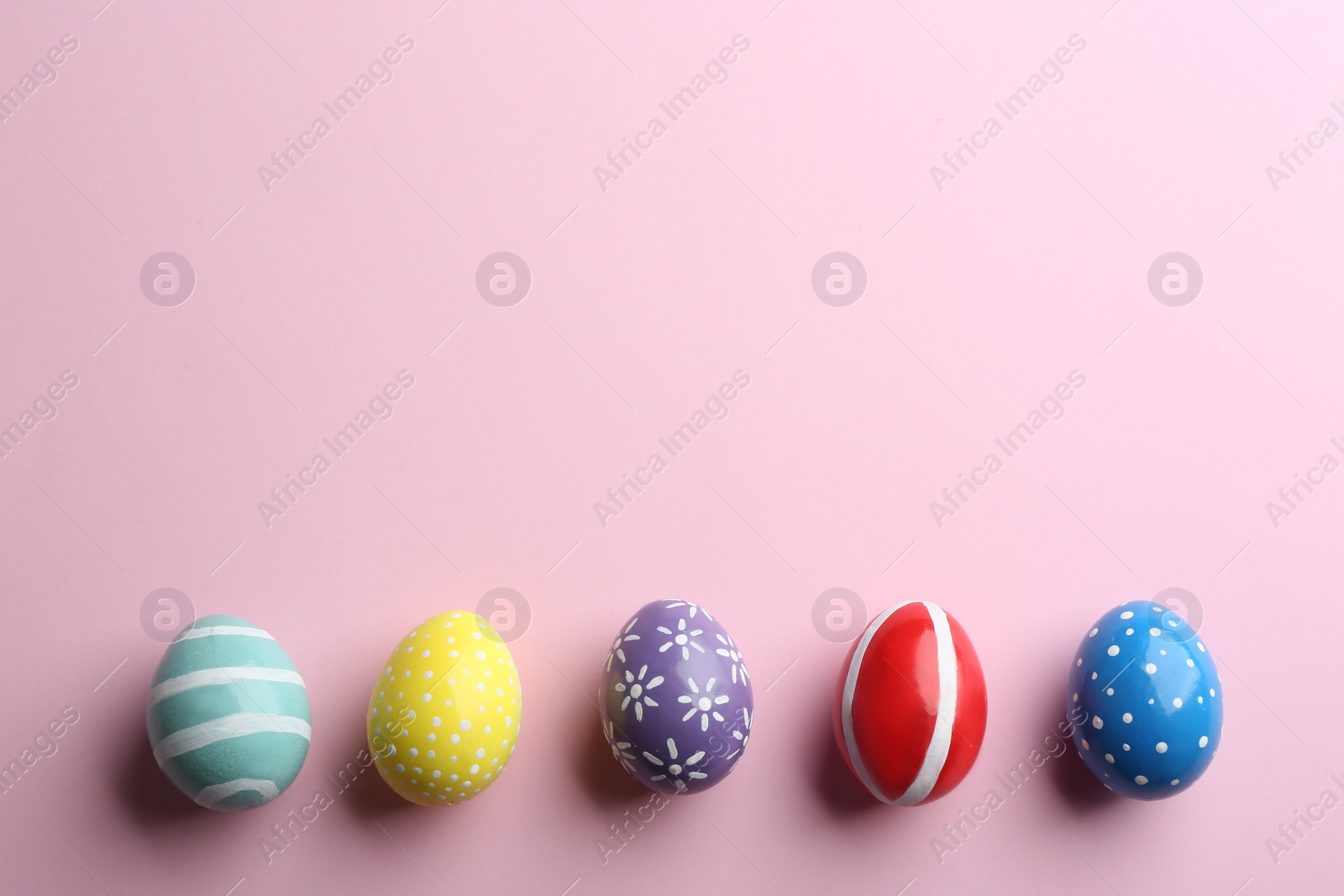 Photo of Flat lay composition of painted Easter eggs on color background, space for text