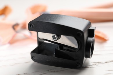 Photo of Black pencil sharpener on white wooden table, closeup