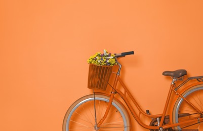 Image of Retro bicycle with wicker basket on orange background