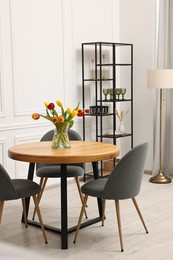 Stylish dining room interior with comfortable furniture and beautiful tulips