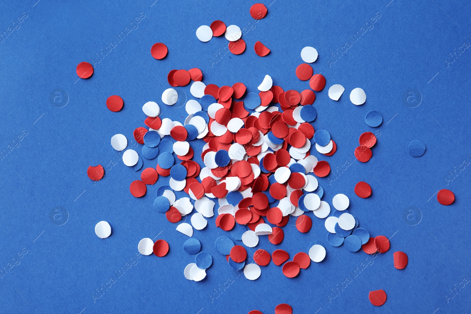 Photo of Many bright confetti on color background, top view. USA Independence Day