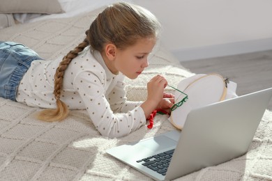 Photo of Little girl learning to embroider with online course at home. Time for hobby