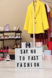 Photo of Lightbox with phrase SAY NO TO FAST FASHION on floor indoors