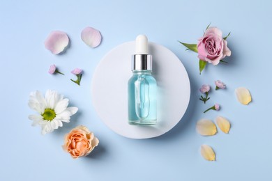 Photo of Bottle of cosmetic serum, beautiful flowers and petals on light blue background, flat lay