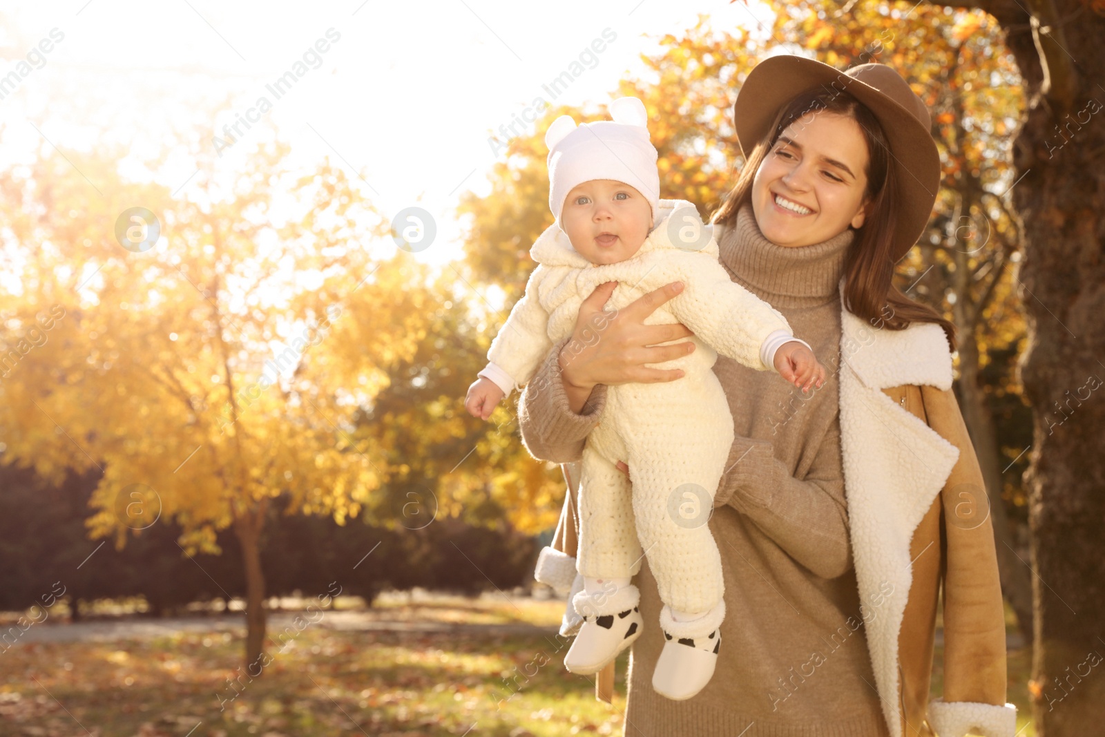 Photo of Happy mother with her baby daughter in park on sunny autumn day, space for text