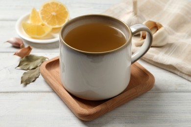 Hot delicious bouillon in cup on white wooden table