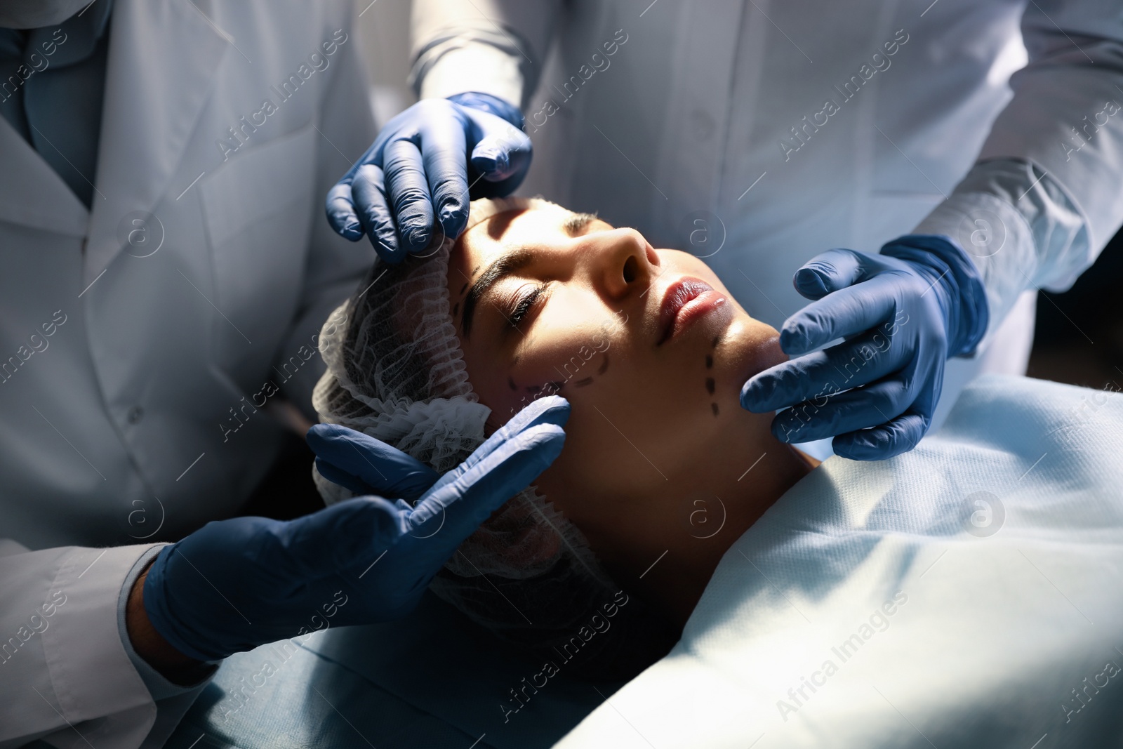 Photo of Doctor and nurse preparing female patient for cosmetic surgery in clinic