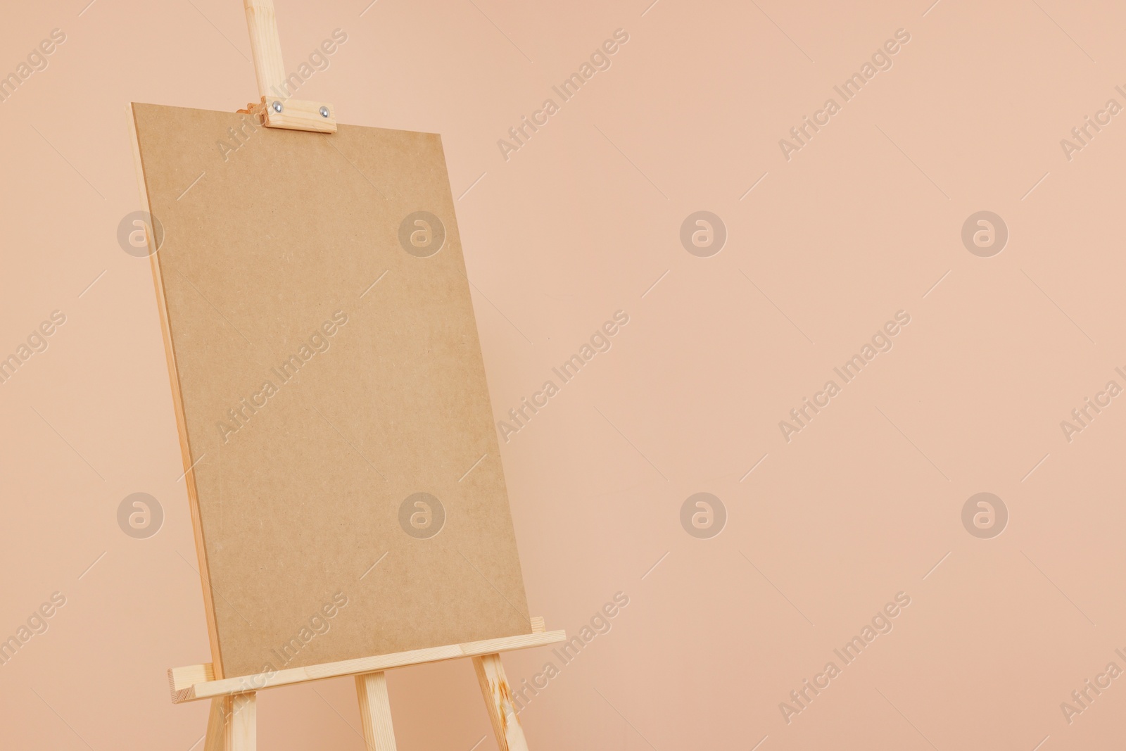 Photo of Wooden easel with blank board on beige background. Space for text