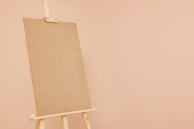 Photo of Wooden easel with blank board on beige background. Space for text