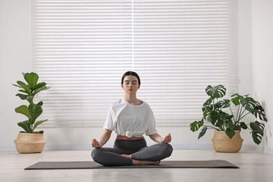 Photo of Beautiful girl meditating on mat in yoga studio